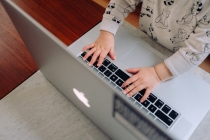 dziecko pisze na komputerze pracującej mamy